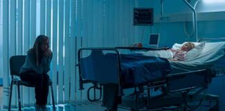 hospital room with child in bed and adult sitting nearby