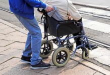 Doctors Sound Alarm On Caregiving Burnout Caregiver pushing person in wheelchair over curb