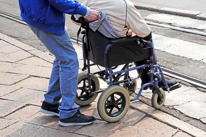 shutterstock_1198667221 Caregiver pushing person in wheelchair over curb