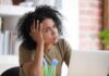 Woman resting head on hand while looking away at a laptop