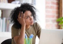 The Missing Deficiency Keeping Your Fatigue Locked In Woman resting head on hand while looking away at a laptop
