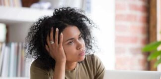 Woman resting head on hand while looking away at a laptop