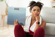 Woman holding a bathroom scale with a frustrated expression