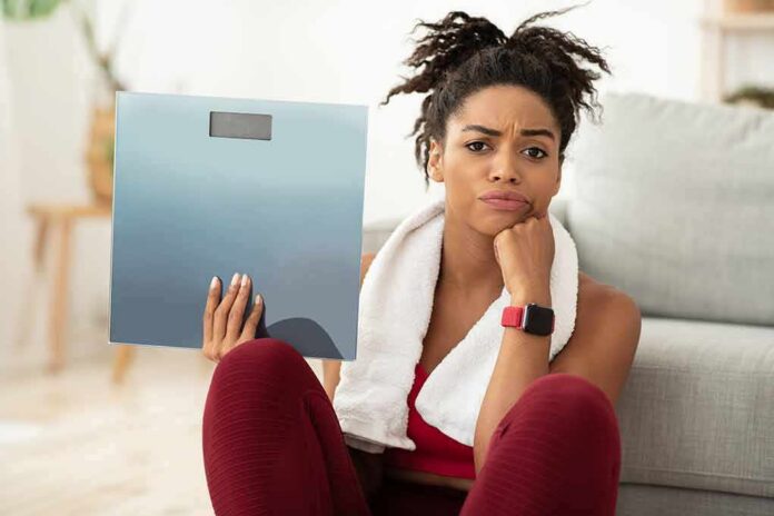 Woman holding a bathroom scale with a frustrated expression