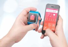 The 5 Best Smart Rings in 2026, Tested by Fitness Editors hands holding a smartwatch and a smartphone with health app