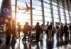 Passengers queue inside an airport terminal at sunset