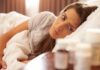 Insomnia Fix Rewinds Your DNA Clock Woman lying in bed looking at pill bottles on a bedside table