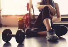 Your Ultimate Body Recomposition Guide person resting on gym floor with dumbbell and water bottle