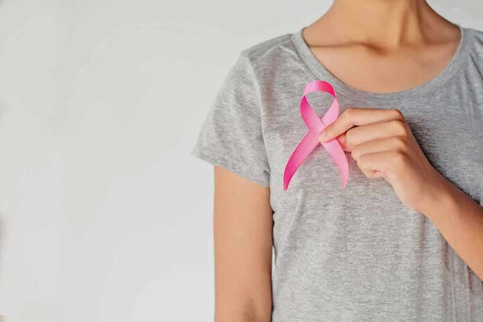 Person holding a pink ribbon on a gray shirt