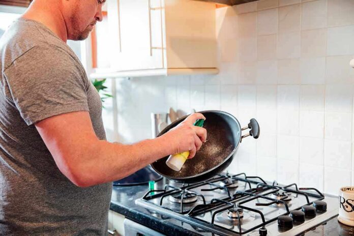 Man spraying oil into a wok over a gas stove