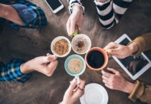 Hands holding five coffee mugs in a toast