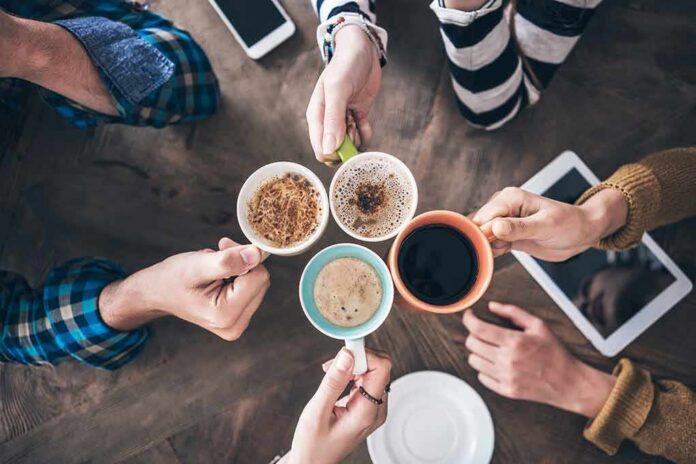 shutterstock_1143280904 Hands holding five coffee mugs in a toast