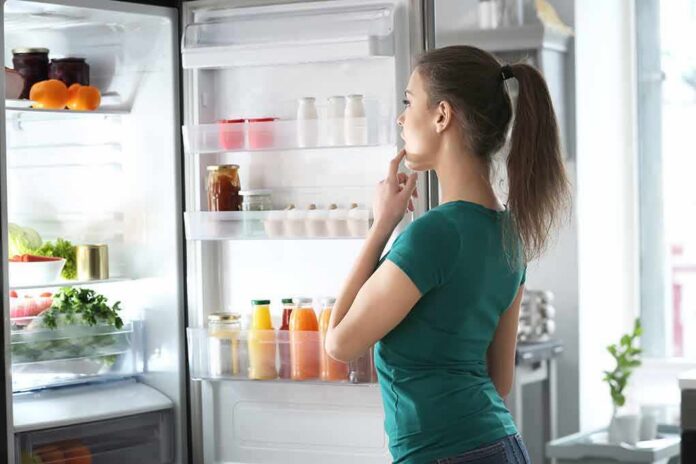 shutterstock_1432491728 Woman looking into an open refrigerator