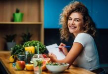 Keto Isn’t a Trend – It’s Clinical Smiling woman writing in a notebook at a kitchen counter with fresh produce