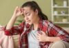 Silent Heart Failure Warning Signs young woman on a couch holding her chest and forehead