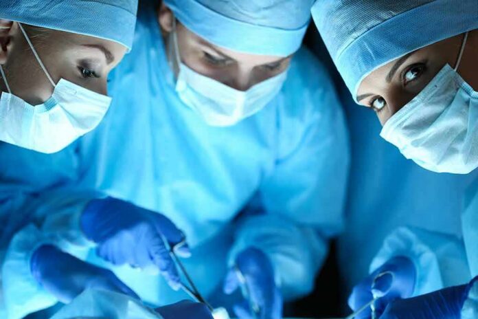 shutterstock_345190367 surgeons in blue scrubs performing an operation