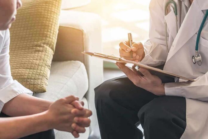 Doctor with clipboard talking to patient on a sofa